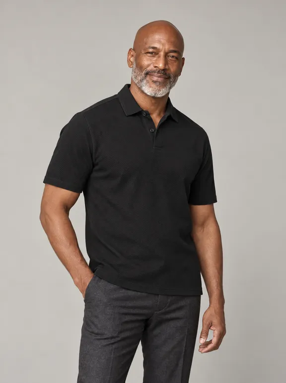 13927-grindlays-black-polo_short_sleeve_polo_collar_two_buttons_fabric_4610_model_035_pose_013_polo_regular_material_pima_pique_bg_11_nopocket_untucked_e0g0h0_upper_body_three_quarter.png